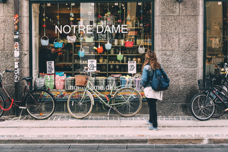 Copenhagen, Denmark - August 10, 2016.  Young woman looking at store window of Notre Dame shopping in Copenhagen with bicycles parked. It offers Nordic design in kitchenware, textiles and practical storage solutions.のeditorial素材