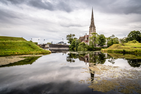 Church reflected on water pond in Churchill Park in Copenhagen a cloudy day of summer near sunset.の写真素材