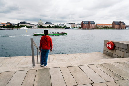 Copenhagen, Denmark - August 12, 2016: Unidentified kid in steps of Opera house of Copenhagen a cloudy day of summer against Copenhagen cityscapeのeditorial素材