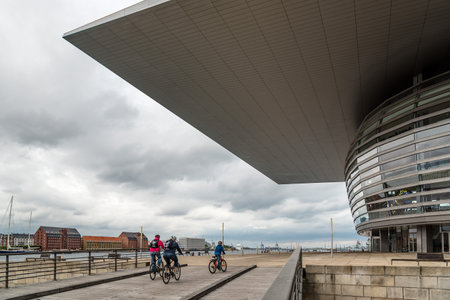 Copenhagen, Denmark - August 12, 2016: Exterior view of the Copenhagen Opera House against cityscape with cyclists. It is the national opera house of Denmark, and among the most modern opera houses in the world.のeditorial素材