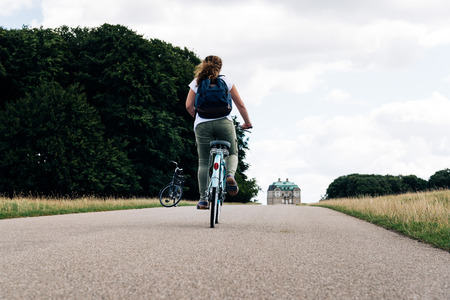 Pretty young woman riding bike in a country road in the park