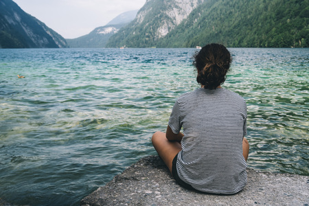 Young woman sitting by the beautiful lakeの写真素材