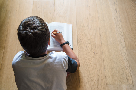 Little boy child reading a book. He lies on the floor.の写真素材