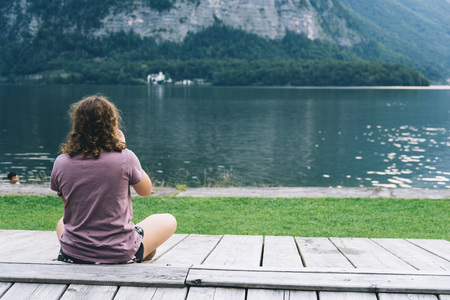 Woman sitting back on pier at lakesideの写真素材