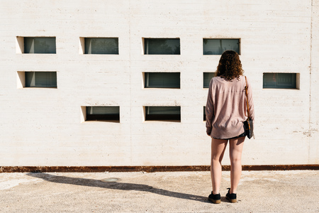 Young woman standing against  white wall