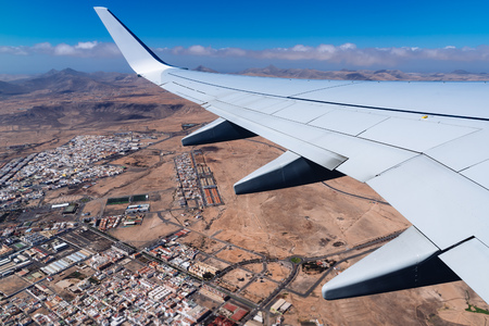 Wing of airplane taking off Fuerteventura Airport, above cityの写真素材