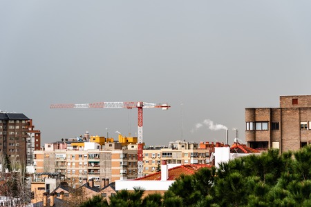 Cityscape with construction crane against gray sky.