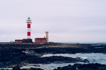 Toston Lighthouse at coastline against cloudy sky