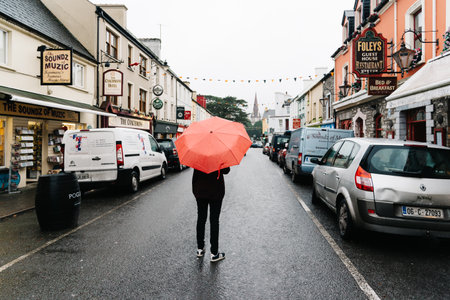 Woman with red umbrella in the middle of street  in small Irishのeditorial素材