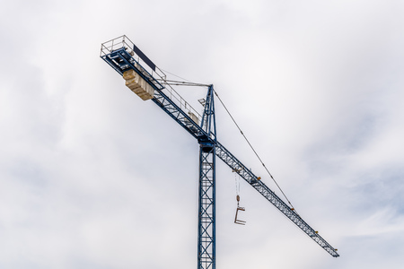 Low angle view of construction crane against cloudy skyの写真素材