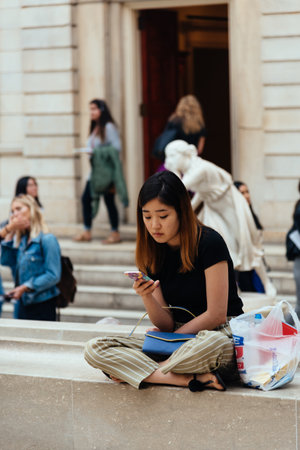 Young woman sitting on museum surfing the internet