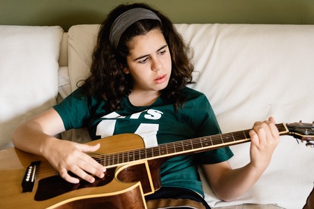 Girl practicing chords on acoustic guitarの写真素材