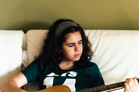 Girl practicing chords on acoustic guitarの写真素材