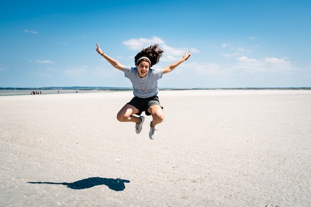 Portrait of woman jumping on the beachの写真素材