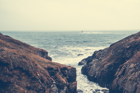 Cliffs and lighthouse in Brittany a misty day