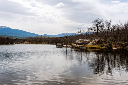 Scenic view of lake and reflections on the water against mountains. Ponton Alto reservoir in...