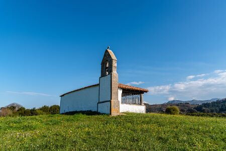 Small chapel in meadow against the mountains