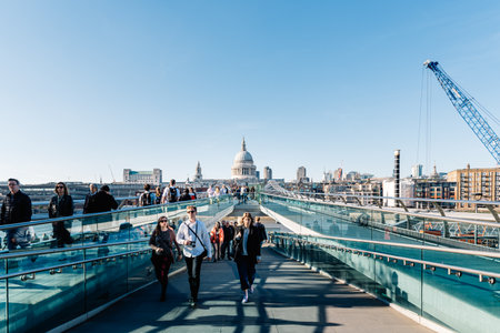 Unidentified people crossing Millennium Bridge against St Paul Cathedral in Londonのeditorial素材
