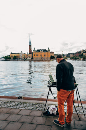 Artist painting the cityscape of the Riddarholmen Island and Gamla Stan by the sea in Stockholmのeditorial素材