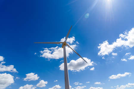 Wind turbines for power generation on hill against blue sky