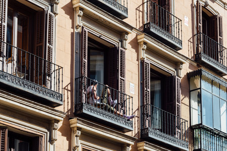 Unidentified man sitting on balcony of old residential building in historic centre of Madridのeditorial素材