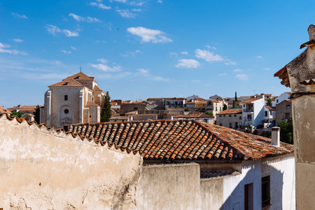 View of small town with church and picturesque houses with plastered facade and ceramic tile roofs on a sunny dayの写真素材