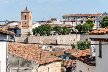 View of small town with church and picturesque houses with plastered facade and ceramic tile roofs...