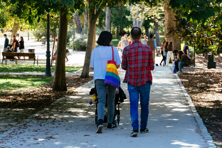 Young couple walking with a baby stroller in the retiro park in Madridのeditorial素材