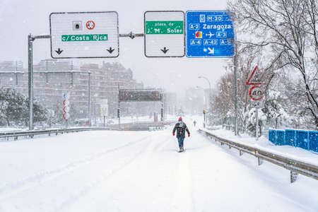 People walking on city street covered in snow during heavy snowfallの写真素材