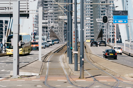 People crossing and vehicles driving on the Erasmusbrug bridge over New Meuse riverのeditorial素材
