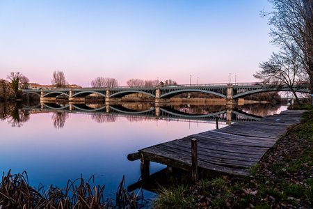 Pier and Enrique Estevan Iron Bridge reflected on the Tormes River at sunsetの写真素材