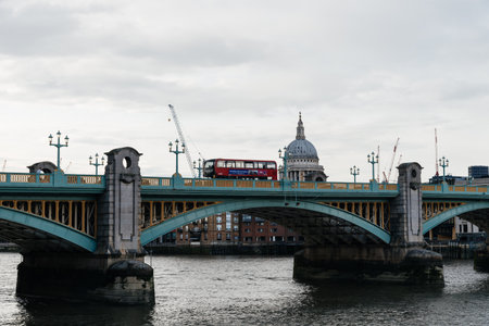 LONDON, UK - August 26, 2023: Red Bus crossing Southwark Bridge over Thames River against St Paul Cathedral in the City of London. View at duskのeditorial素材