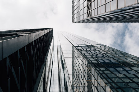 Low angle view of modern office buildings in the City of London and reflections on curtain wall facade. View against blue sky with white clouds with space for copyの写真素材