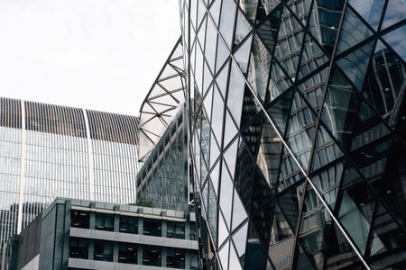 London, UK - August 25, 2023: Low angle view of modern office buildings in the City of London and reflections on curtain wall facade. View against blue sky with white cloudsのeditorial素材