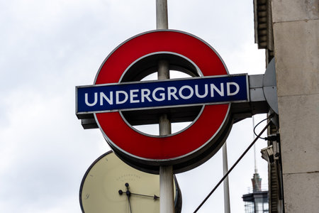 LONDON, UK - August 26, 2023: Close-up view of the London Underground sign and logo against cloudy sky. Concept of public transportのeditorial素材