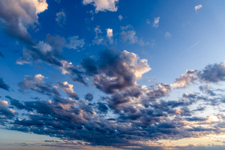 Beautiful white puffy clouds against blue sky during dramatic sunset.の写真素材