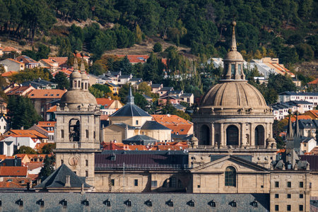 A landscape view of the Royal Monastery of San Lorenzo de El Escorial in Spain, showcasing its architectural grandeur against a backdrop of town and nature.の写真素材
