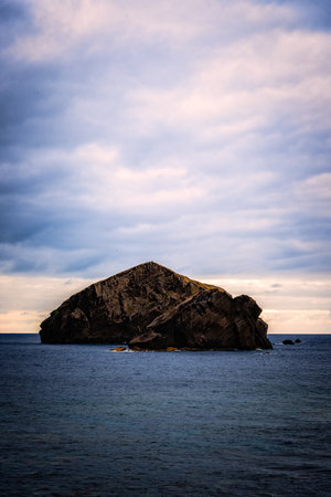 Two rocky islets stand tall in the Atlantic Ocean under a cloudy sky, creating a dramatic seascape near Praia dos Mosteiros, Azores.の写真素材