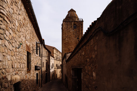 An old stone tower rises at the end of a narrow, winding street in Trujillo, Extremadura, Spain, showcasing its rich heritage.の写真素材