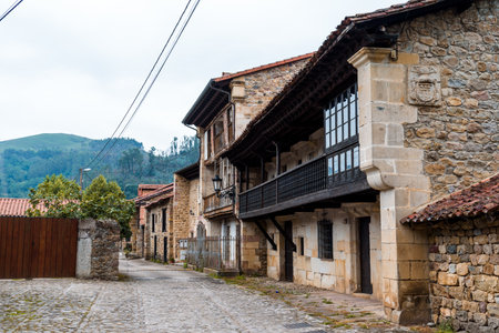 A charming street in the Saja River Valley features traditional stone buildings and cobblestone...