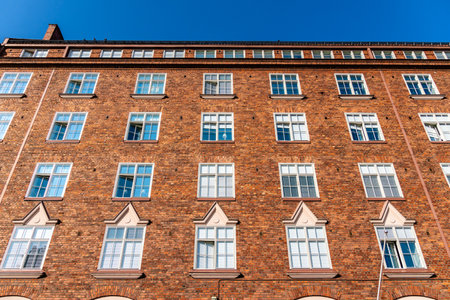 An upward view shows the detail of a red brick apartment building under a clear blue sky in...