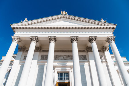 A low-angle shot of the Helsinki Cathedral's facade, capturing its neoclassical architecture and statues against a clear blue sky.の写真素材