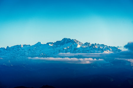 Majestic snow-capped mountains rise above a layer of clouds under a clear blue sky. Peaks of Europeの写真素材