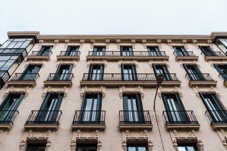 Facade of an elegant apartment building in Madrid, Spain, showing classic architectural details and wrought-iron balconies.の写真素材