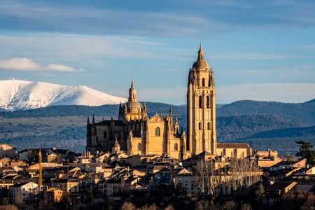 Picturesque view of Segovia, Spain, with the cathedral and snowy Guadarrama mountains in the background, showcasing a stunning skyline.の写真素材
