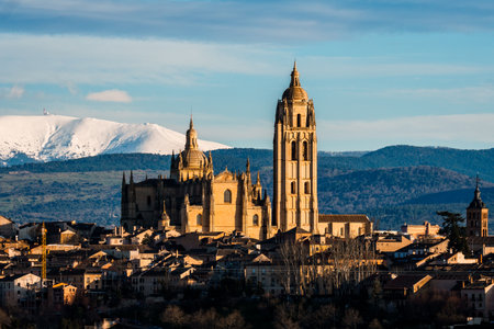 Picturesque view of Segovia, Spain, with the cathedral and snowy Guadarrama mountains in the background, showcasing a stunning skyline.の写真素材