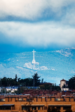 Gigantic cross of Valley of the Fallen standing out against blue mountains and cloudy sky, seen from Madridの写真素材