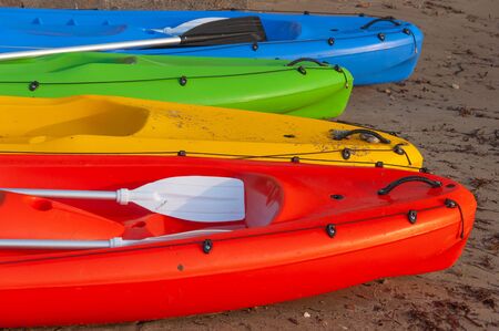 multi-colored kayaks on the sandy shore