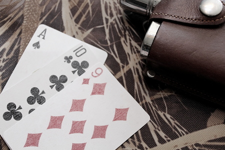 Flask with alcohol and playing cards on camouflage material.の写真素材