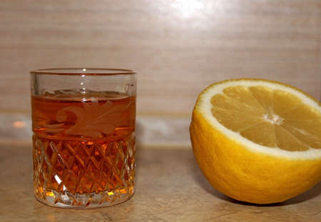 Alcoholic drink poured into a transparent glass in combination with lemonの写真素材